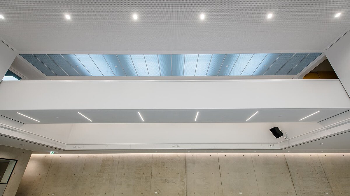 Innenansicht des Markgraf-Georg-Friedrich-Gymnasiums in Kulmbach mit großen Flachdach-Fenstern, die natürliches Licht durch die Decke in den Raum lassen.