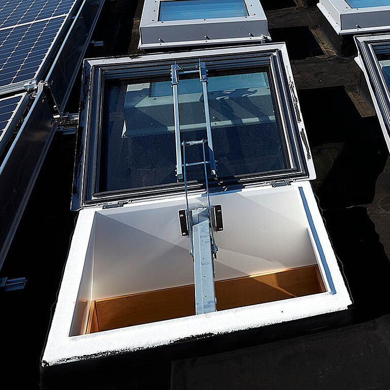Geöffnetes LAMILUX Flachdach Fenster FE RWA auf Industrie-Flachdach mit sichtbarer Antriebstechnik und rechteckigem Dachaufsatz