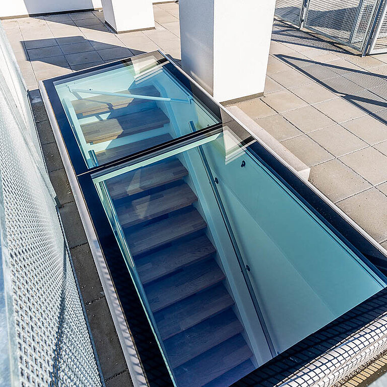 Geöffneter LAMILUX Flachdach Ausstieg mit transparenter Verglasung und integrierter Treppe für sicheren Dachzugang