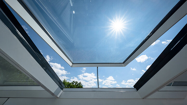 Wohnhaus in Freiburg mit modularen Glasdach von LAMILUX, Blick durch das geöffnete Dach in den Himmel.