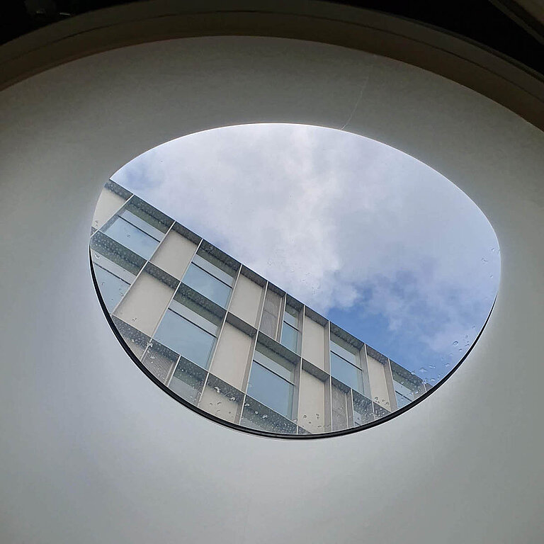 LAMILUX Flachdach Fenster F100 rund mit weißem Innenrahmen, Blick nach außen durch runde Tageslichtöffnung