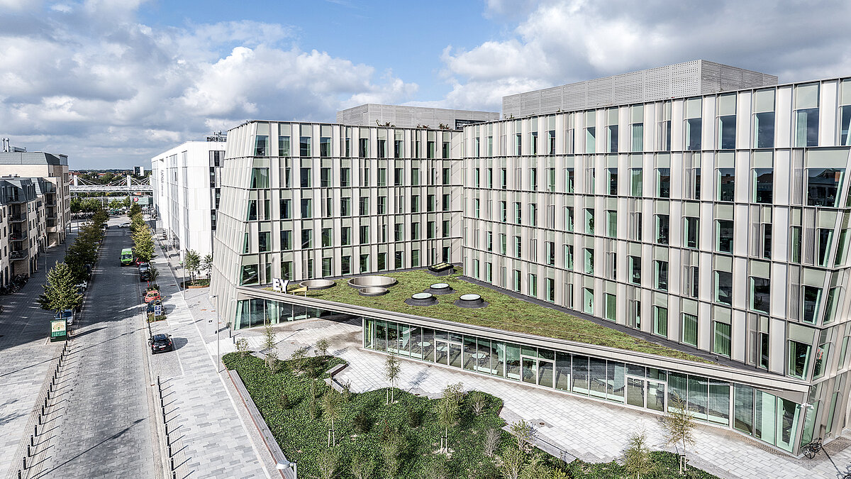 Ernst & Young Bürogebäude mit moderner Fassadenarchitektur, begrüntem Dach und Innenhof