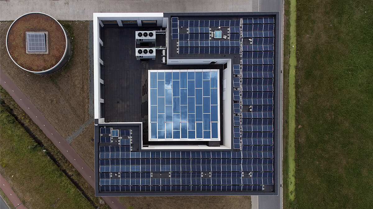 Luftaufnahme eines Flachdachs mit zentralem Glasdach und umliegenden Solarmodulen