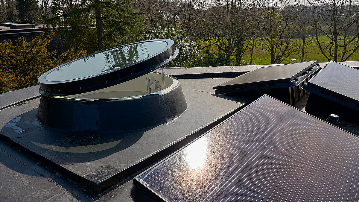 Geöffnete runde LAMILUX Lichtkuppel auf Flachdach mit Solarmodulen