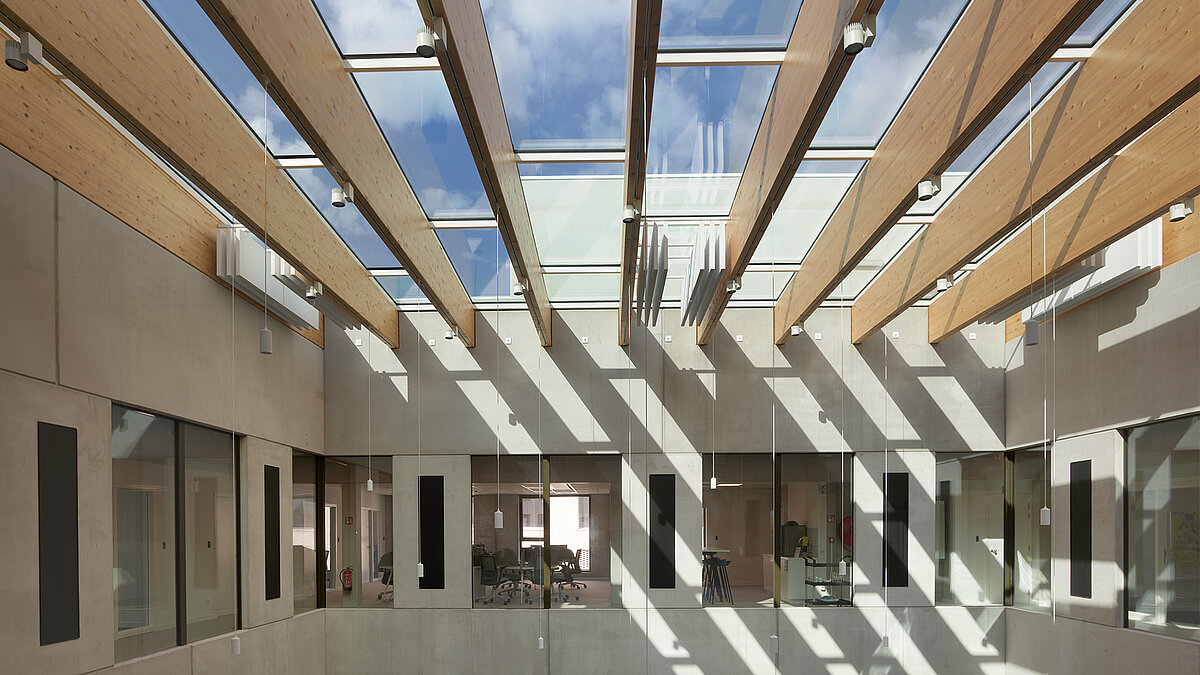 Atrium mit Holzlamellen-Überdachung und großzügigem Glasdach für natürlichen Tageslichteinfall