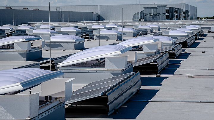 Flachdach mit Lichtkuppeln und Solarpanelen auf Industriegebäude