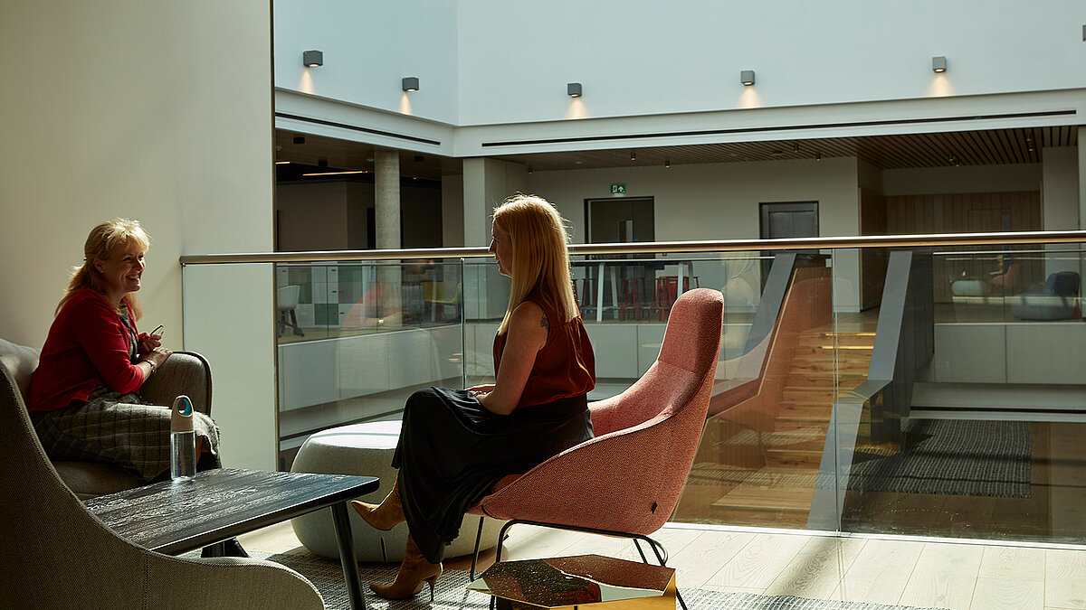 Modernes Atrium mit Sitzbereich und zwei Personen im Gespräch