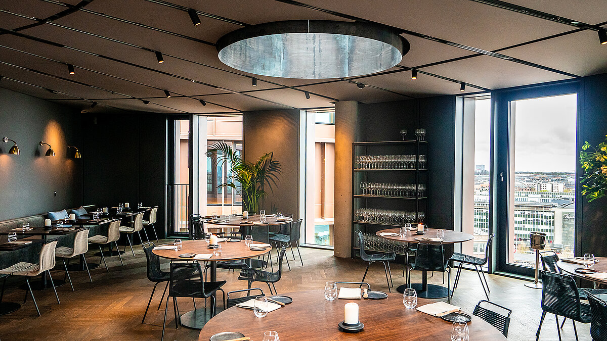 Modernes Restaurant mit runden Tischen, großem Oberlicht und Panoramablick über die Stadt