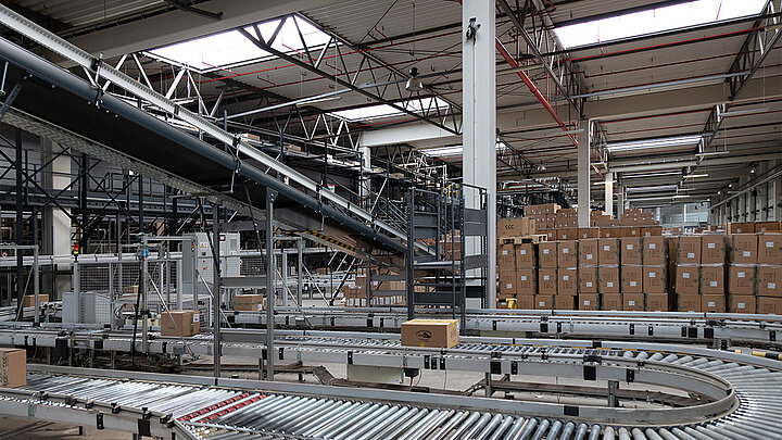 Blick in eine Produktionshalle mit Förderband. Darüber sorgen Lichtbänder für Tageslichteinfall