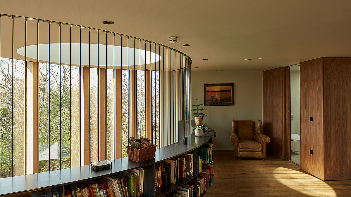 Wohnbereich mit rundem LAMILUX Flachdach Fenster, Holzlamellen und Einbauregal