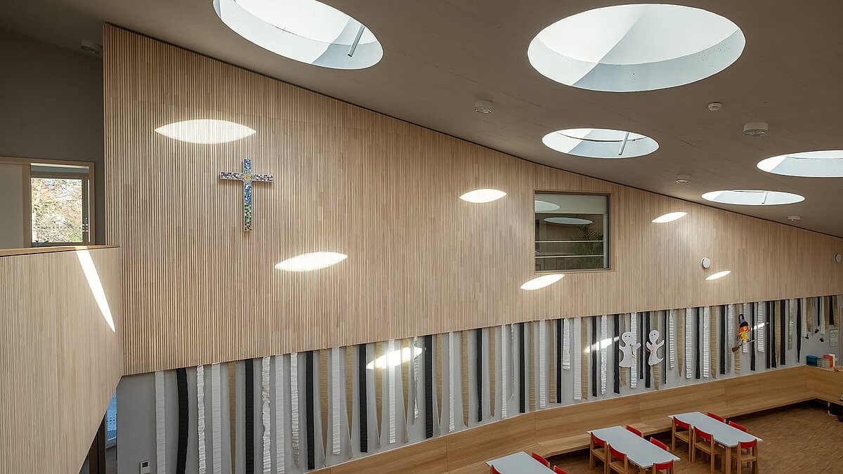 Innenansicht des Kindergartens St. Severin mit runden Flachdach-Fenstern, die natürliches Tageslicht hereinlassen.