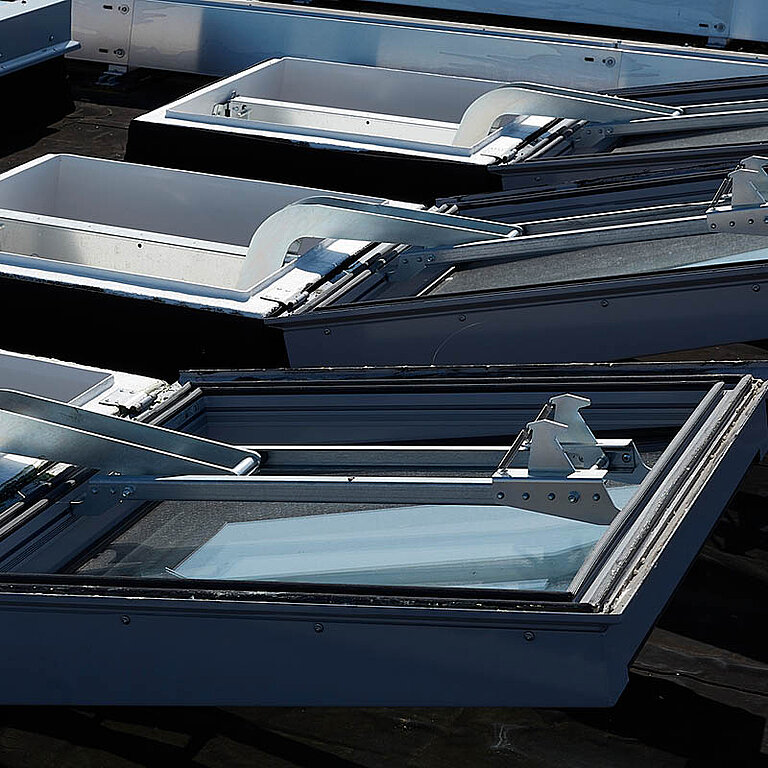 Mehrere LAMILUX Flachdach Fenster FE RWA auf Industrie-Flachdach mit teilweise geöffneter Verglasung