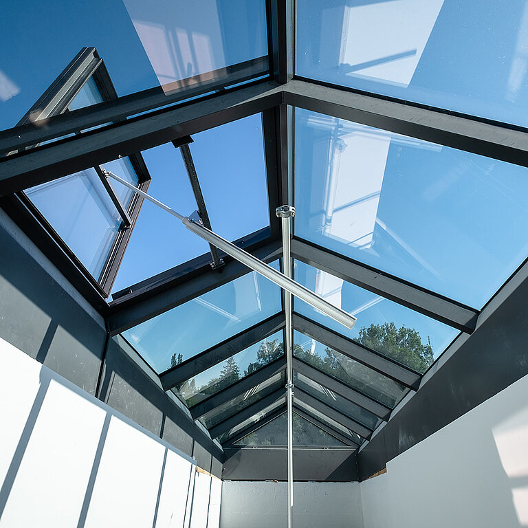Glasdach PR60 mit schwarzem Aluminiumrahmen und Lüftungsflügeln in Satteldachform.
