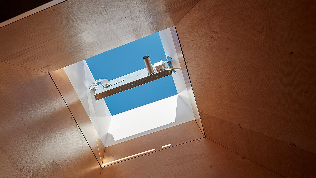 Quadratisches Flachdachfenster in Holzdecke mit Blick auf blauen Himmel
