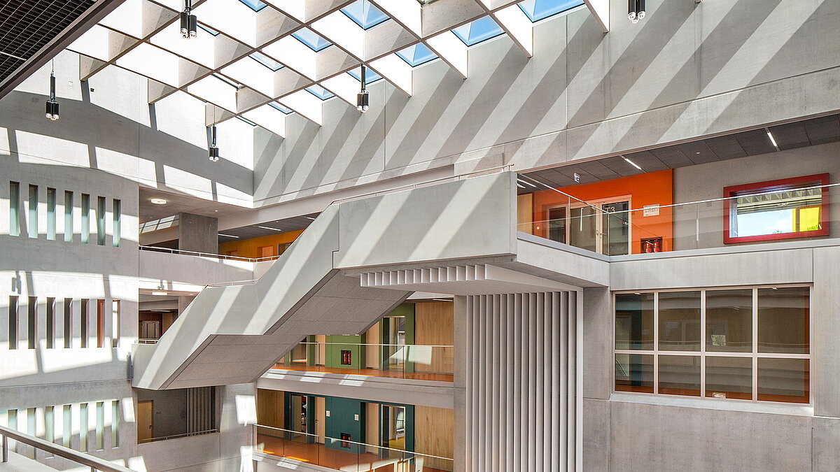 Innenansicht des Willibald-Gluck-Gymnasiums in Neumarkt mit Glasdächern von LAMILUX, modernem Design und farbigen Klassenzimmern.