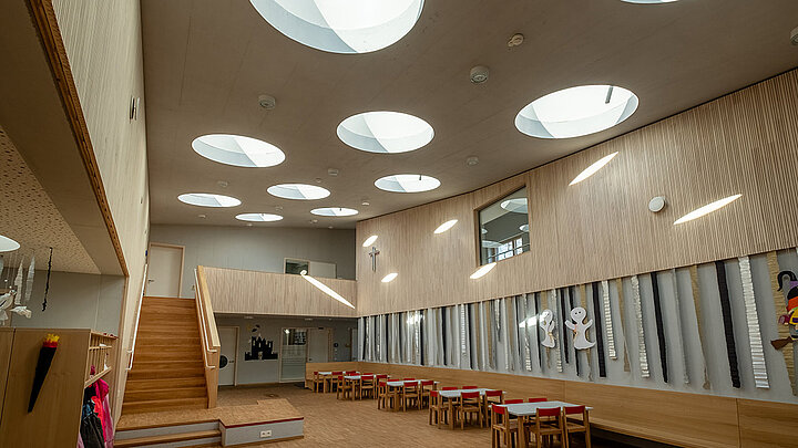 Lichtspiel der runden Flachdach Fenster im Aufenthaltsraum eines Kindergartens | insights by LAMILUX