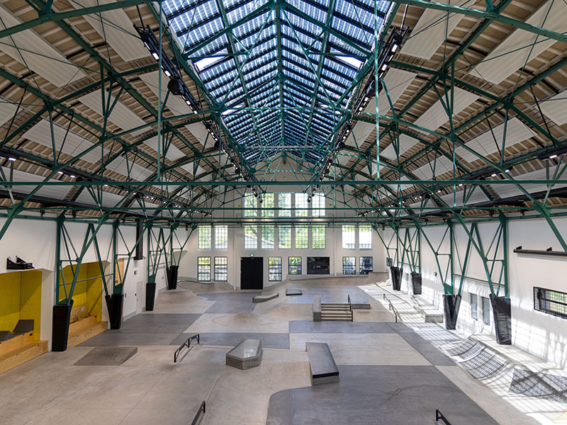 Große Industriehalle mit Stahlkonstruktion und Skatepark im Inneren