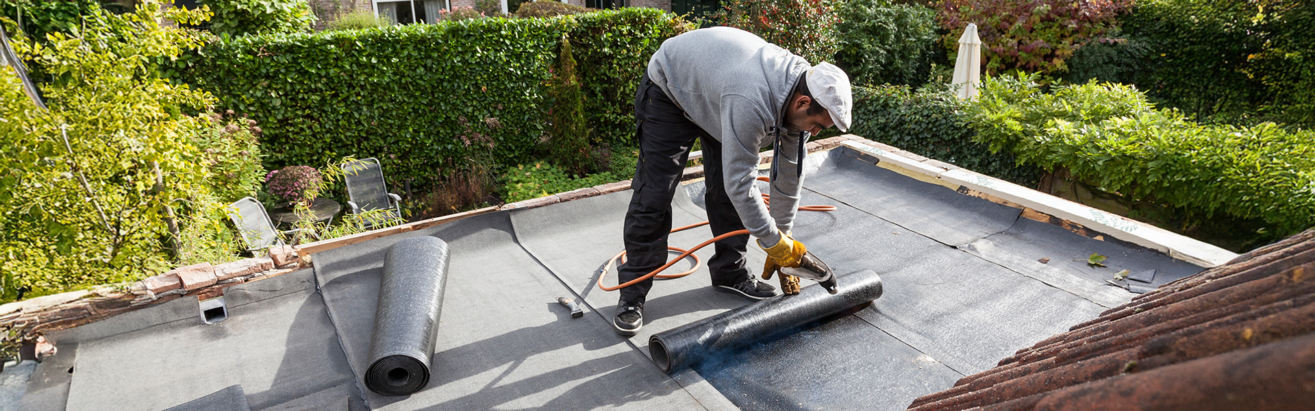 Handwerker schneidet Terrassenplatte bei der Verlegung auf einer Dachterrasse