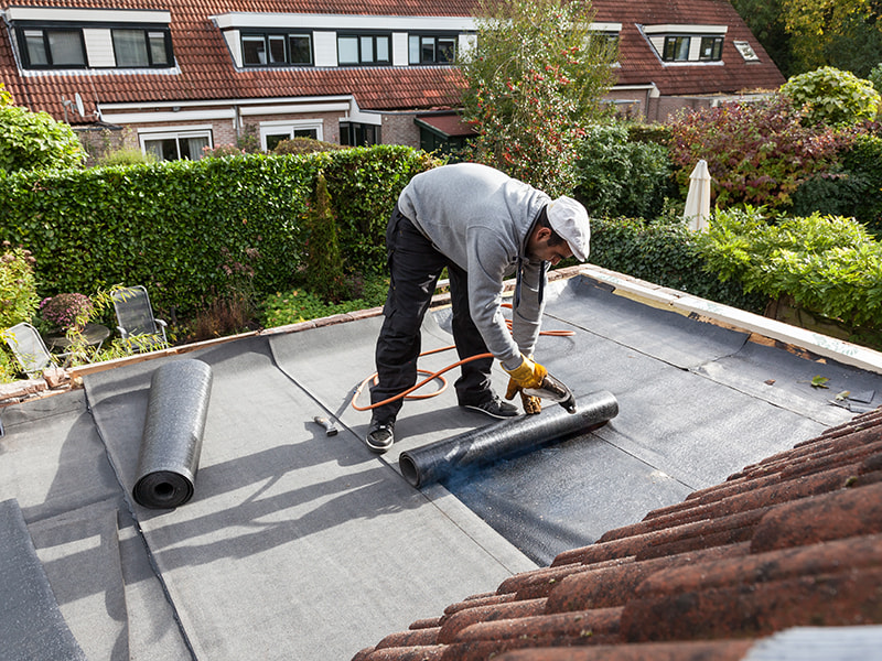 Handwerker schneidet Terrassenplatte bei der Verlegung auf einer Dachterrasse