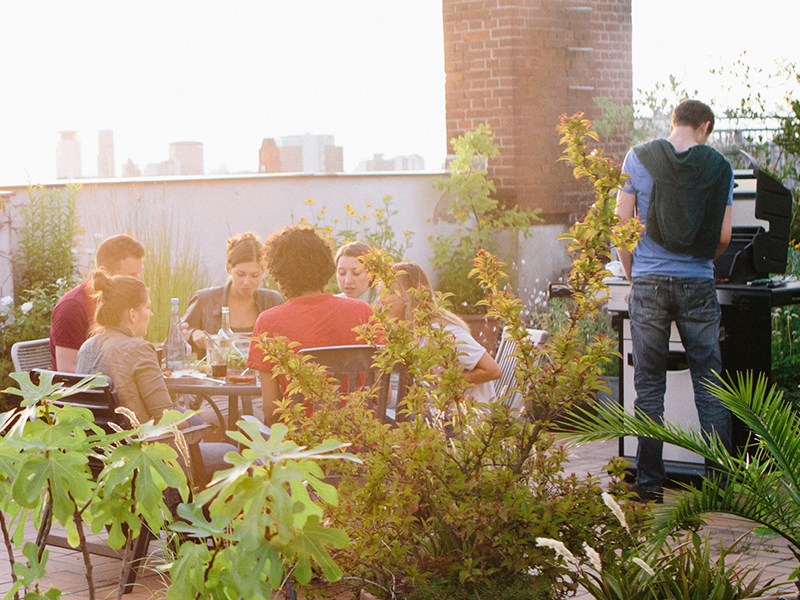 Begrünte Dachterrasse mit Menschen bei Sonnenuntergang.