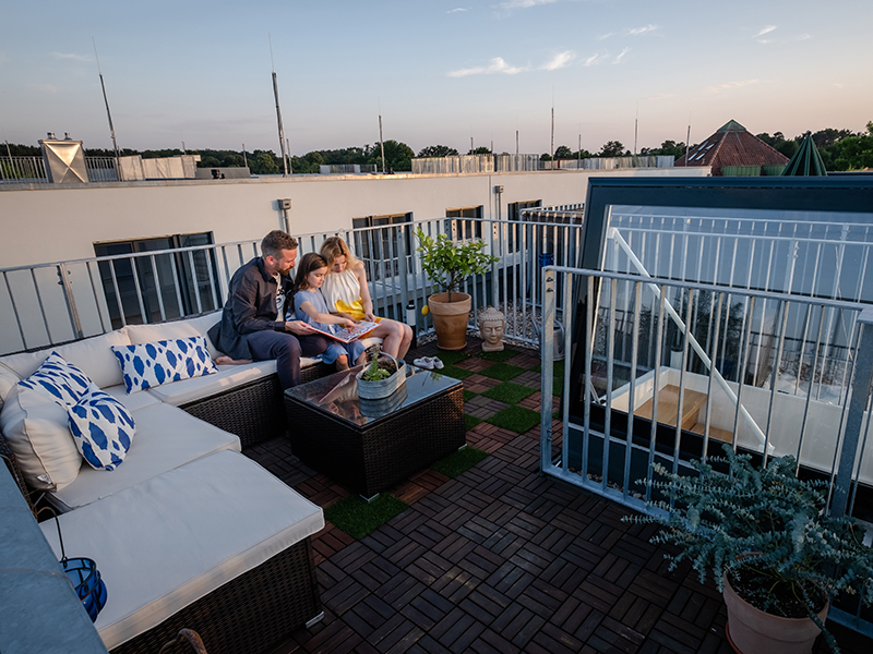  Familie entspannt auf einer stilvollen Dachterrasse bei Abenddämmerung.