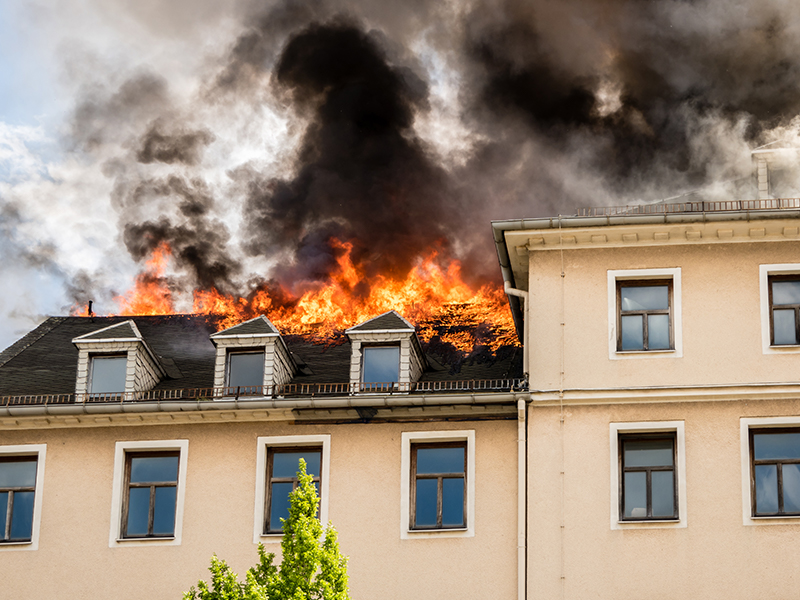 Wohnhaus mit Dachbrand, Flammen und dichter schwarzer Rauch über dem Gebäude
