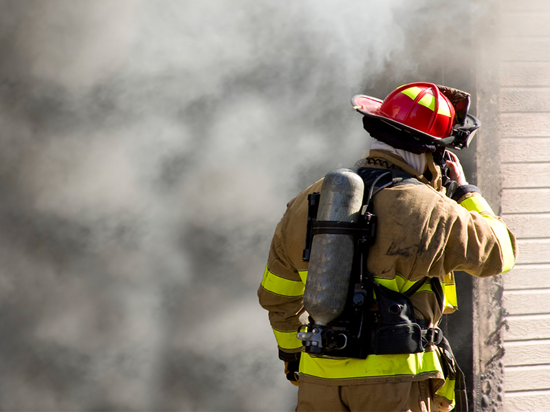 Feuerwehrmann steht vor brennenden Haus