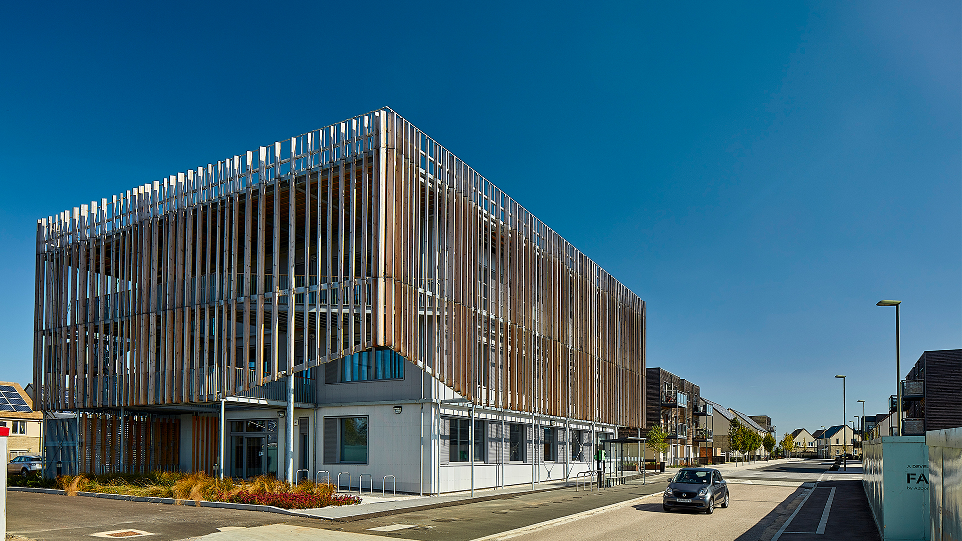 Modernes Bürogebäude mit markanter Holzfassade und vertikalen Lamellen unter blauem Himmel