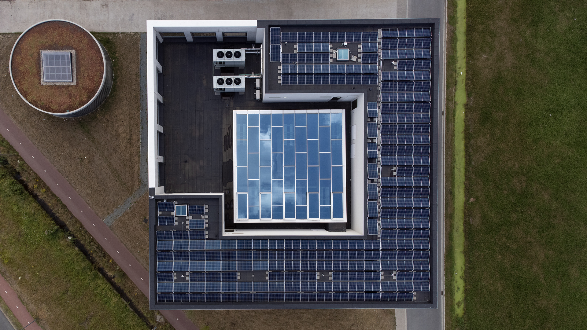 Luftaufnahme eines Flachdachs mit zentralem Glasdach und umliegenden Solarmodulen