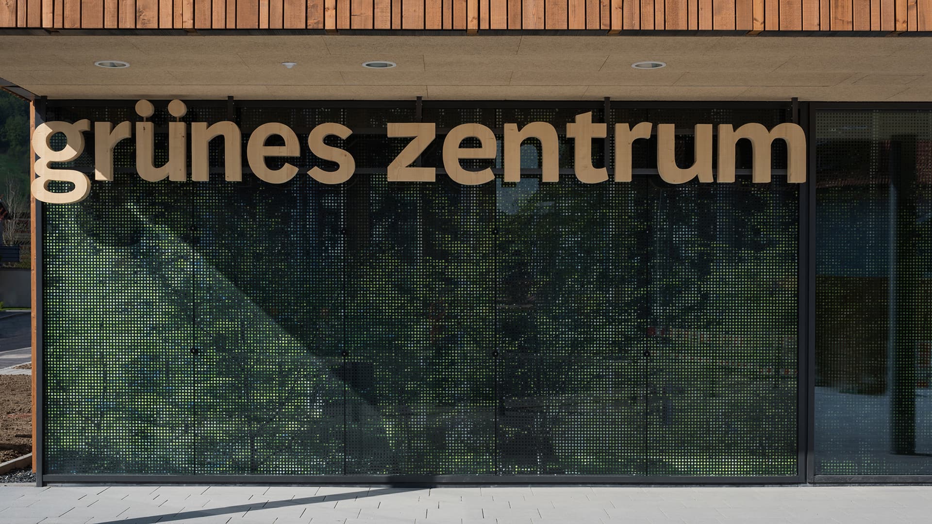 Eingangsbereich des Grünen Zentrums Immenstadt mit moderner Glasfassade und Holzschriftzug.